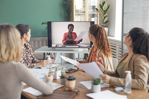 Portrait of African-American businesswoman on computer screen talking to team during online business meeting in office, copy space