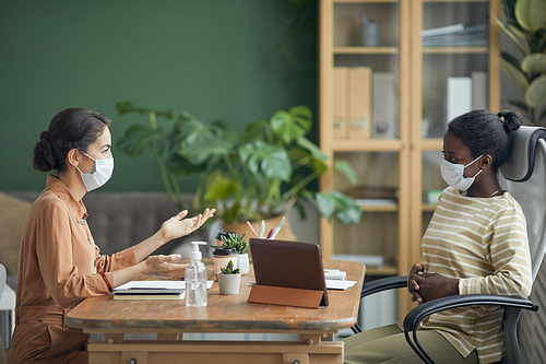 Side view portrait of two businesswomen wearing masks during job interview in office, copy space