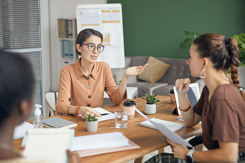 Group of modern female entrepreneurs talking animatedly during business meeting in office, copy space