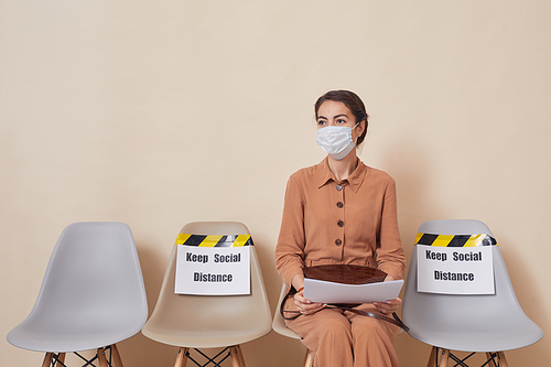 Portrait of one youmg woman waiting in line with social distancing warning, copy space