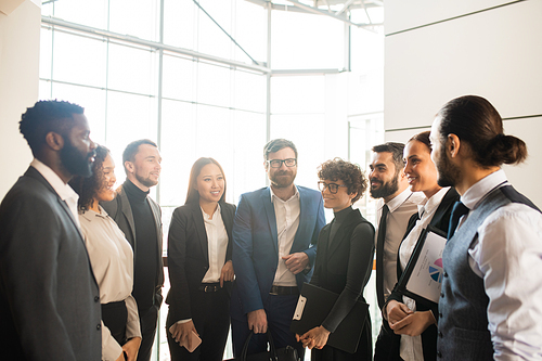 Staff of modern company standing in circle and brainstorming about development strategy in office