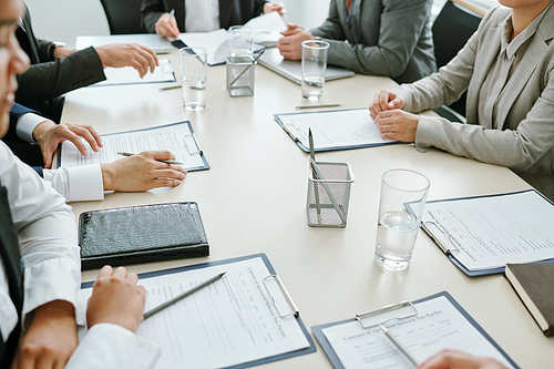 Large group of business partners or colleagues or conference participants learning financial papers or contract at meeting in boardroom