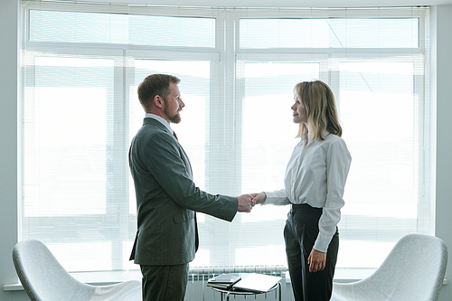 Confident hr manager shaking hand of young successful applicant while congratulating her on beginning of new career after interview