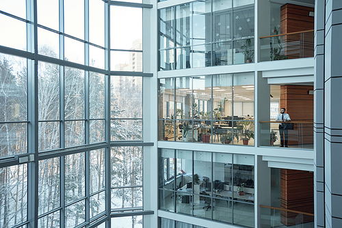 Interior of contemporary multi-floor business center with large windows and many offices in front of them