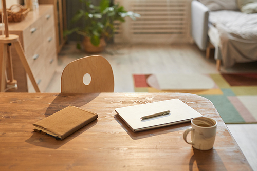 Warm toned background image of cozy home office with laptop on wooden desk scene lit by sunlight, copy space