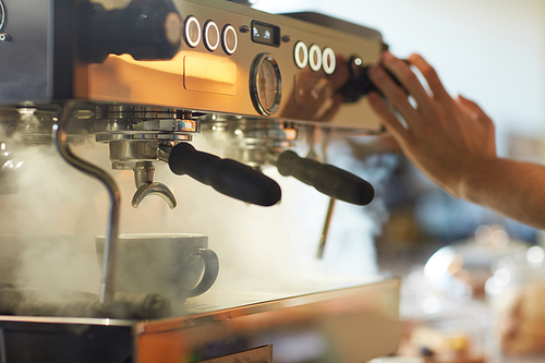 Close up of steaming coffee machine in cafe or coffee shop with unrecognizable barista pressing buttons, copy space