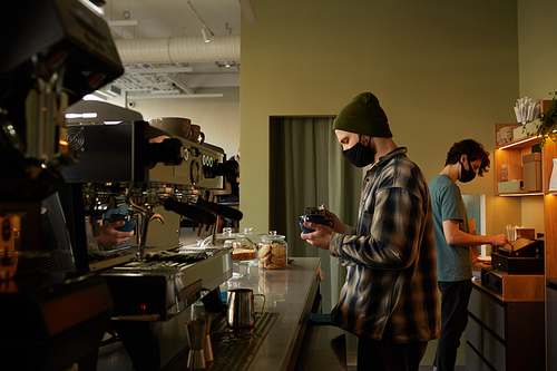 Side view portrait of male barista making fresh coffee while working at bar counter in cafe , copy space