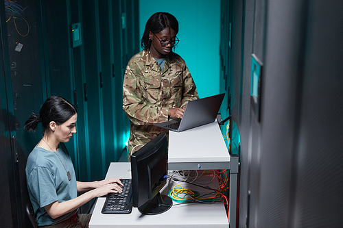 Portrait of two military young woman using computers while working together in server room and setting up network