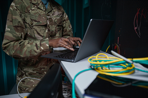 Cropped shot of unrecognizable African-American woman wearing military uniform using computer while setting up network in server room, copy space