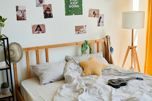 Background image of cozy teenage bedroom interior with a lot of accessories and ukulele on comfortable bed, copy space