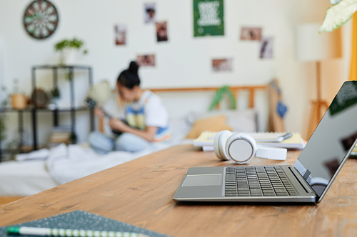 Background image of teenage bedroom with focus on laptop in foreground, copy space