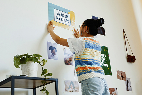 Portrait of modern teenage girl hanging My room my rules poster on wall in room, copy space