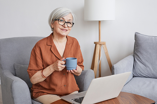 Minimal portrait of modern senior businesswoman looking at camera and enjoying coffee indoors, copy space