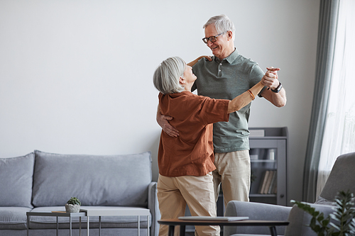 Minimal portrait of loving senior couple dancing at home together, copy space