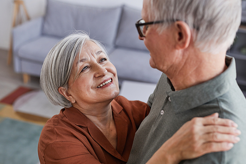 High angle portrait of loving senior couple dancing at home together and looking at each other with love