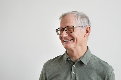 Minimal portrait of smiling senior man looking away while standing against white background, copy space