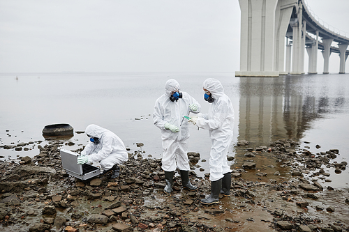 Group of people wearing hazmat suits collecting probes outdoors, toxic waste and pollution concept, copy space