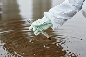 Close up of unrecognizable scientist wearing hazmat suit collecting water samples, focus on gloved hand holding test tube, copy space