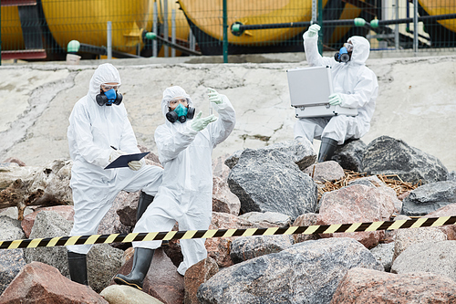 Group of people in hazmat suits working at ecological disaster site, toxic waste and pollution concept, copy space