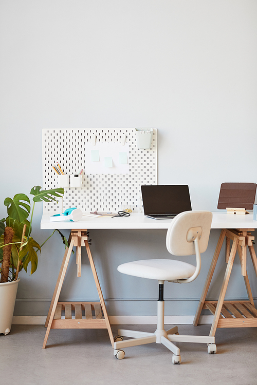 Vertical background image of cozy home office workplace in white decorated by plants, copy space