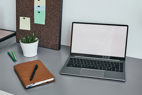 Background image of opened laptop with blank white screen at minimal home office workplace with accessories, copy space