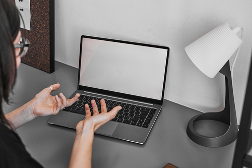 Minimal close up of unrecognizable woman in online meeting gesturing while looking at blank laptop screen, copy space