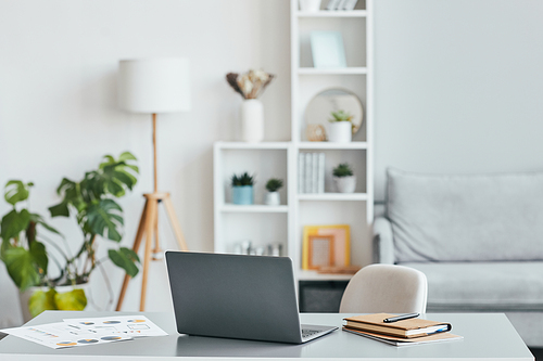 Minimal background image of home office workplace with laptop in white airy interior, copy space