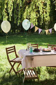 Vertical background image of Summer picnic table outdoors decorated with balloons for Birthday party, copy space