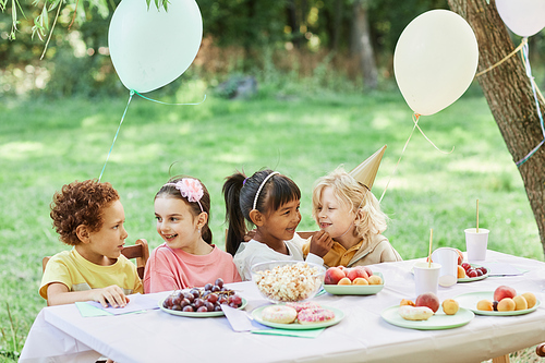 Portrait of diverse group of children at picnic table outdoors enjoying Birthday party in Summer