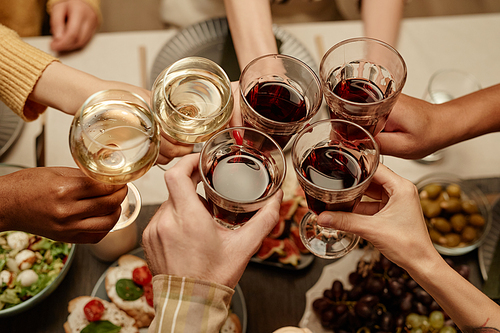Close-up of group of people toasting with glasses of wine at dining table during a party