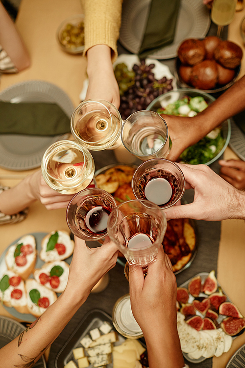Close-up of people toasting with glasses of wine and champagne at dining table