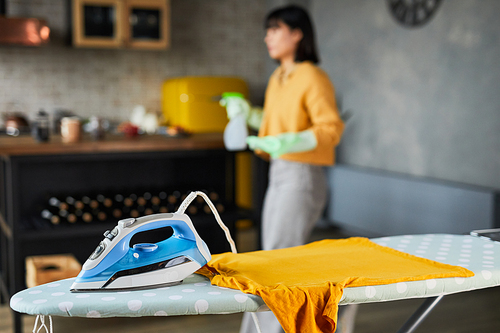 Background image of ironing board with young woman cleaning home, copy space