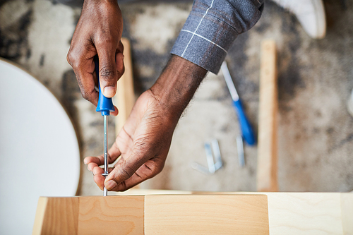 Top view close up of unrecognizable African-American man assembling furniture at home, copy space
