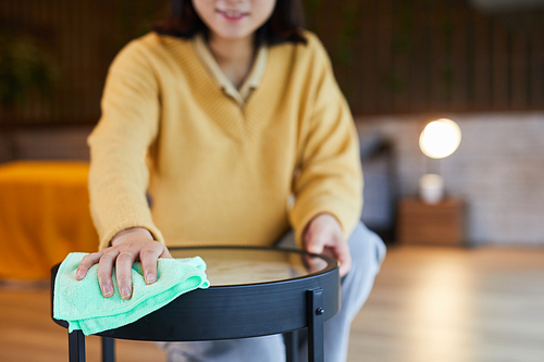Close up of young Asian woman cleaning coffee table in home interior, copy space