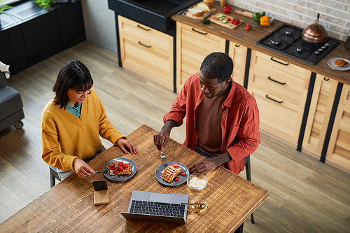Top view portrait of young couple enjoying breakfast in cozy home kitchen, copy space