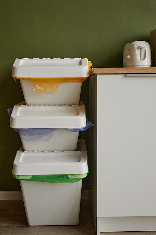 Vertical background image of three waste sorting containers stacked in kitchen, copy space