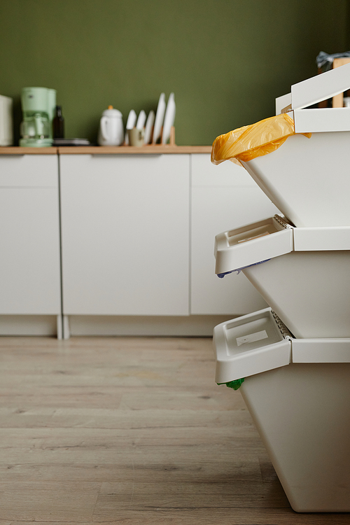 Vertical side view of three waste sorting containers stacked in kitchen, copy space