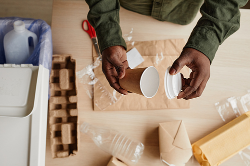 Top view close up of African-American man preparing household waste for recycling, copy space