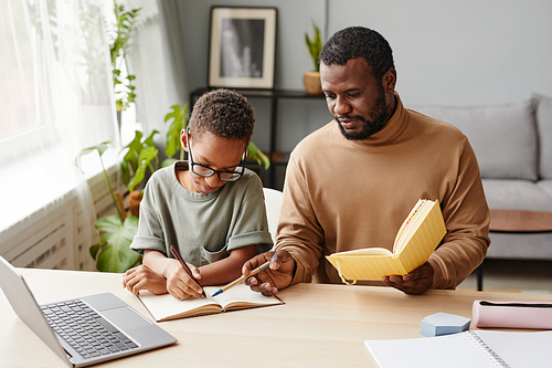Portrait of caring father helping son with homeschooling while studying at home, copy space