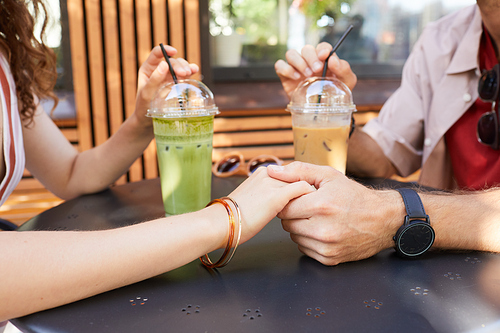 Side view close up of happy couple holding hands at outdoor cafe while enjoying romantic date in Summer, copy space