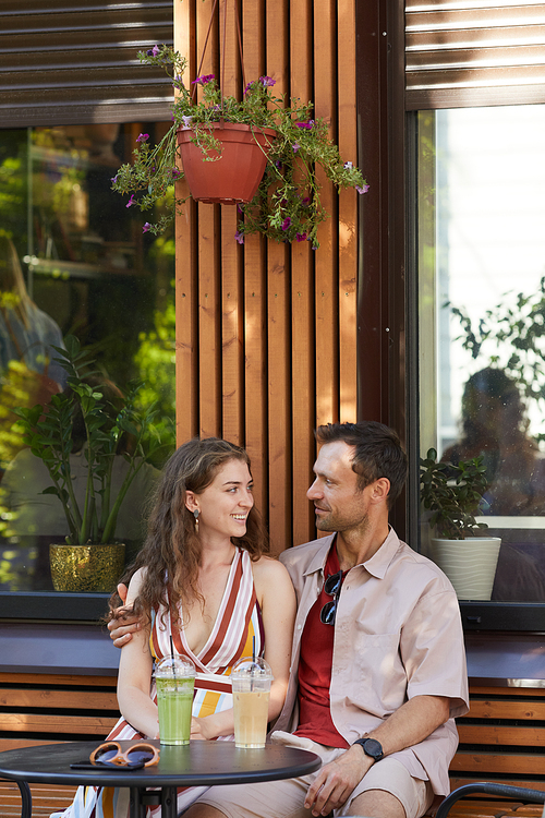 Vertical portrait of happy young couple in outdoor cafe enjoying romantic date in Summer, copy space