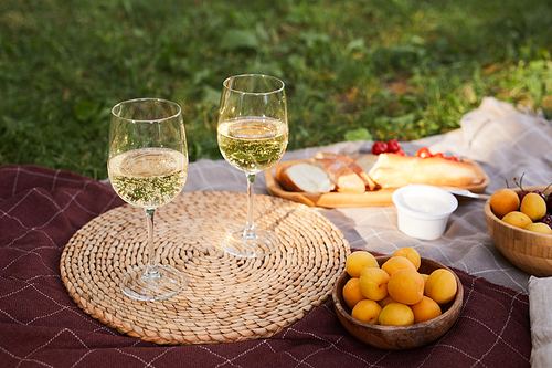 Close up of wine glasses at beautiful picnic setting for romantic date outdoors, copy space