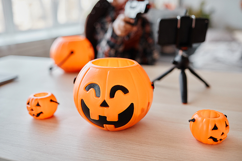 Background image of variations Halloween buckets with smartphone set up on table, livestream background