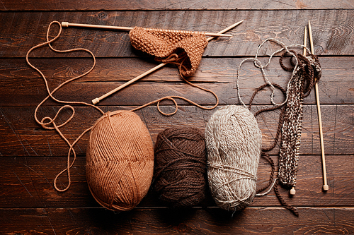 Top view flat lay of wool and knitting supplies on dark wooden table, copy space