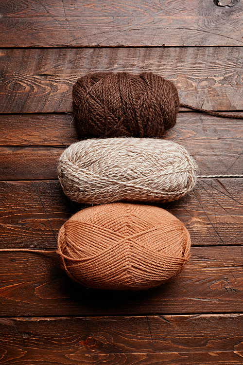 Top down view of neutral colored wool on dark wooden background, knitting and hobby, copy space