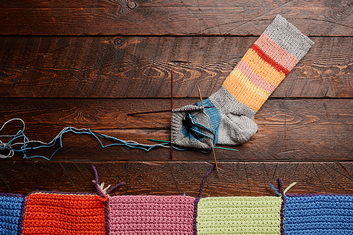 Background image of colorful knit socks on dark wooden background, knitting and hobby, copy space
