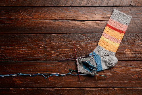 Background image of unfinished knit socks on dark wooden background, knitting and hobby, copy space