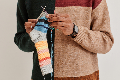 Cropped portrait of young African-American man knitting socks, copy space