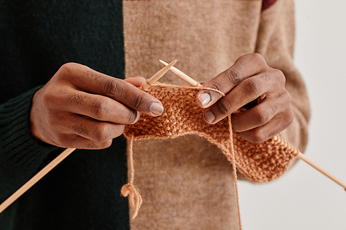 Minimal close up of young African-American man knitting, copy space
