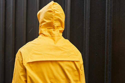 Medium back view shot of unrecognizable man wearing yellow raincoat standing outdoors on rainy day